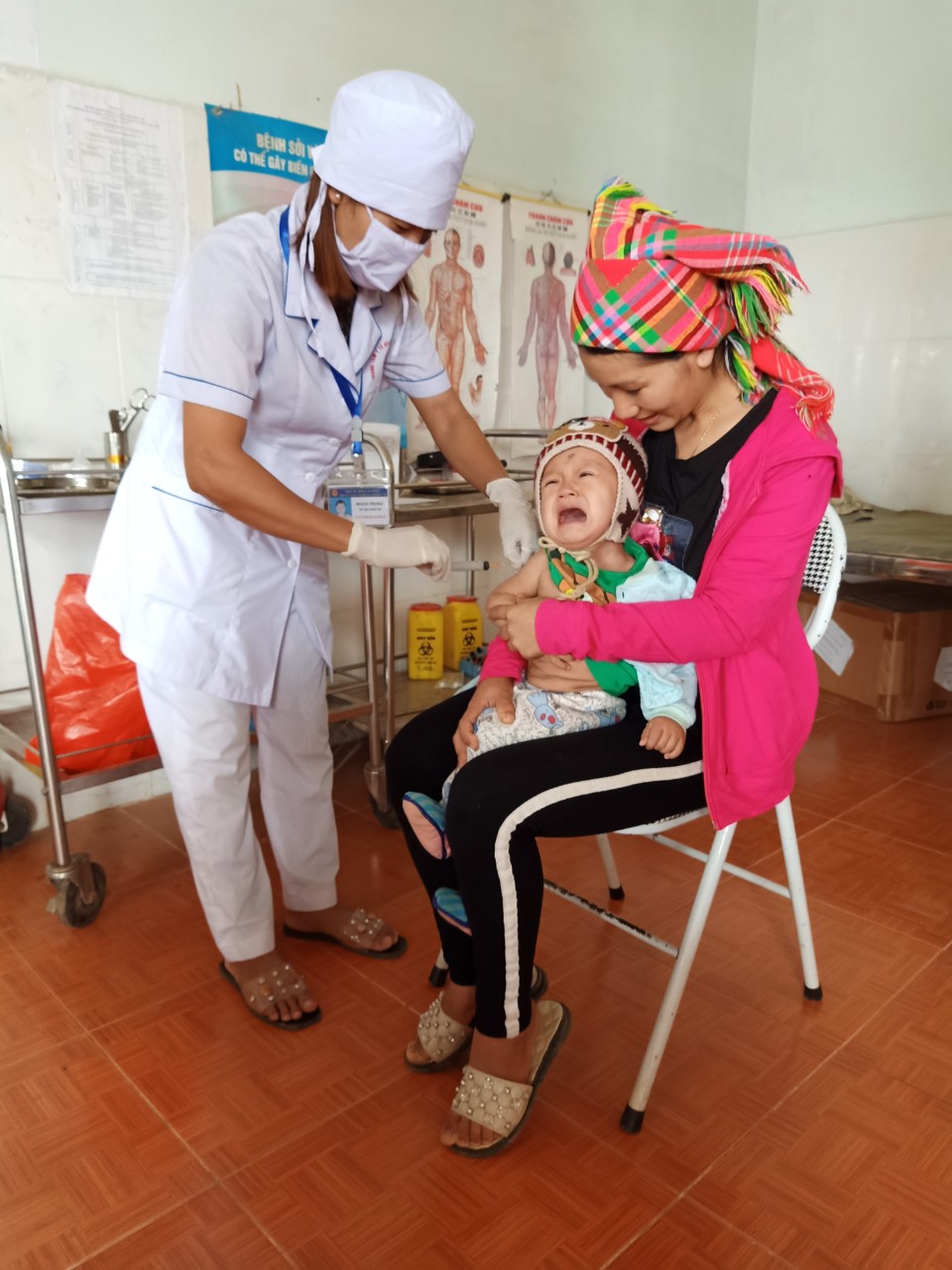 cán bộ trạm y tế Mù cả Mường Tè tiêm vắc xin phòng bệnh cho trẻ